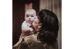 Image Woman holding her baby and kissing its cheek